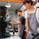 crop baristas against coffee maker and grinder in cafe kitchen
