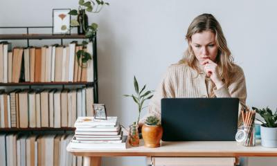pensive woman browsing laptop near books
