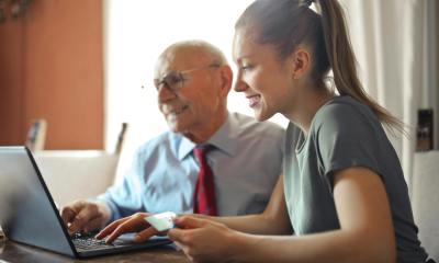 young woman helping senior man with payment on internet using laptop