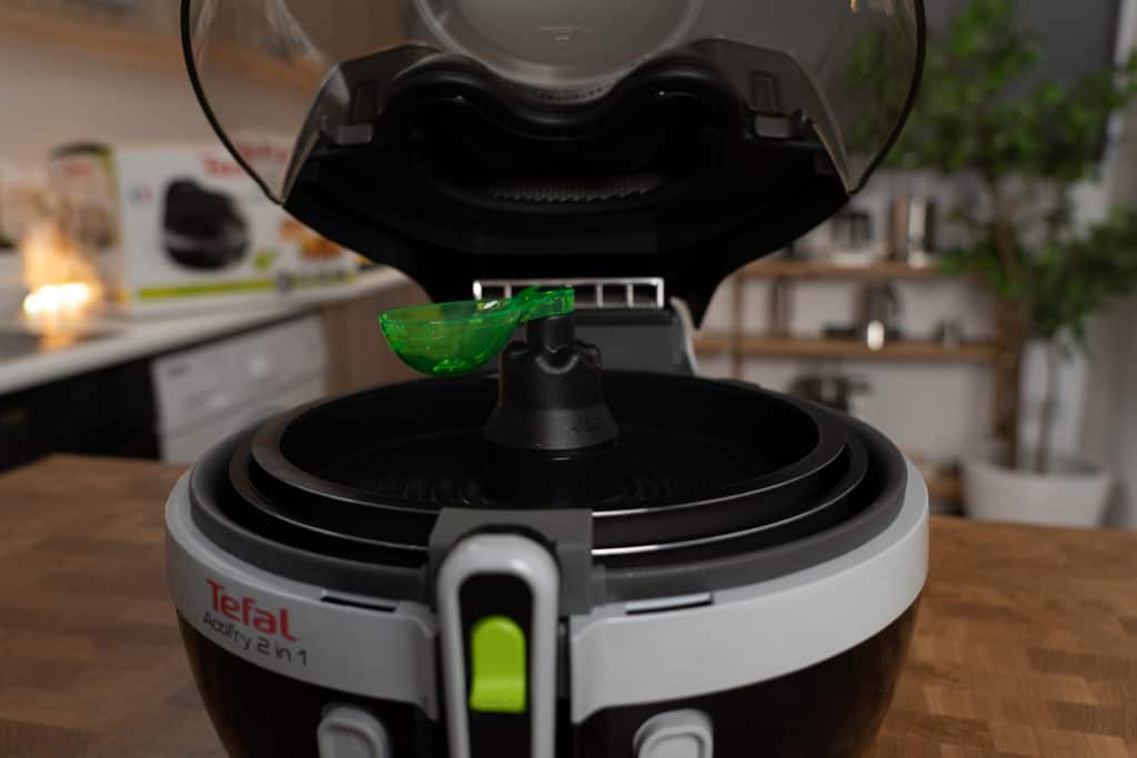 Tefal ActiFry 2in1 YV9601 Gerät mit geöffnetem Deckel zeigt die Grilleinsätze, die zum Lieferumfang gehören sowie den neongrünen Dosierlöffel