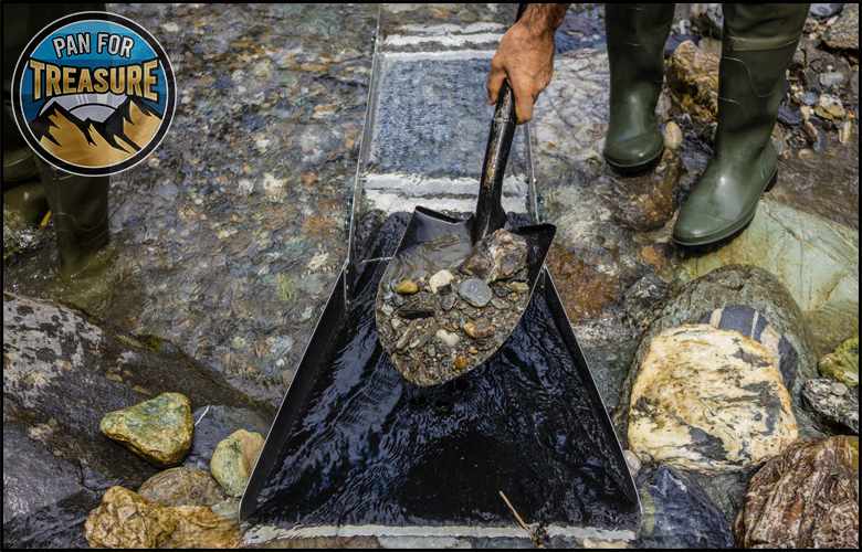 A person in green boots uses a shovel to place rocks and gravel into a sluice box in a stream. A "Pan for Treasure" sign is visible in the upper left corner, highlighting one of the top picks for gold sluice boxes among amateur prospectors.