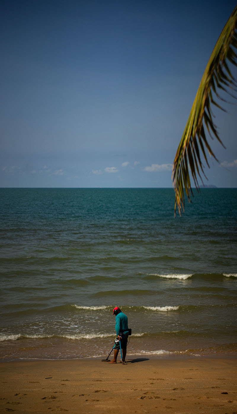 A man standing on a beach with a kite in his hand, enjoying the breeze.