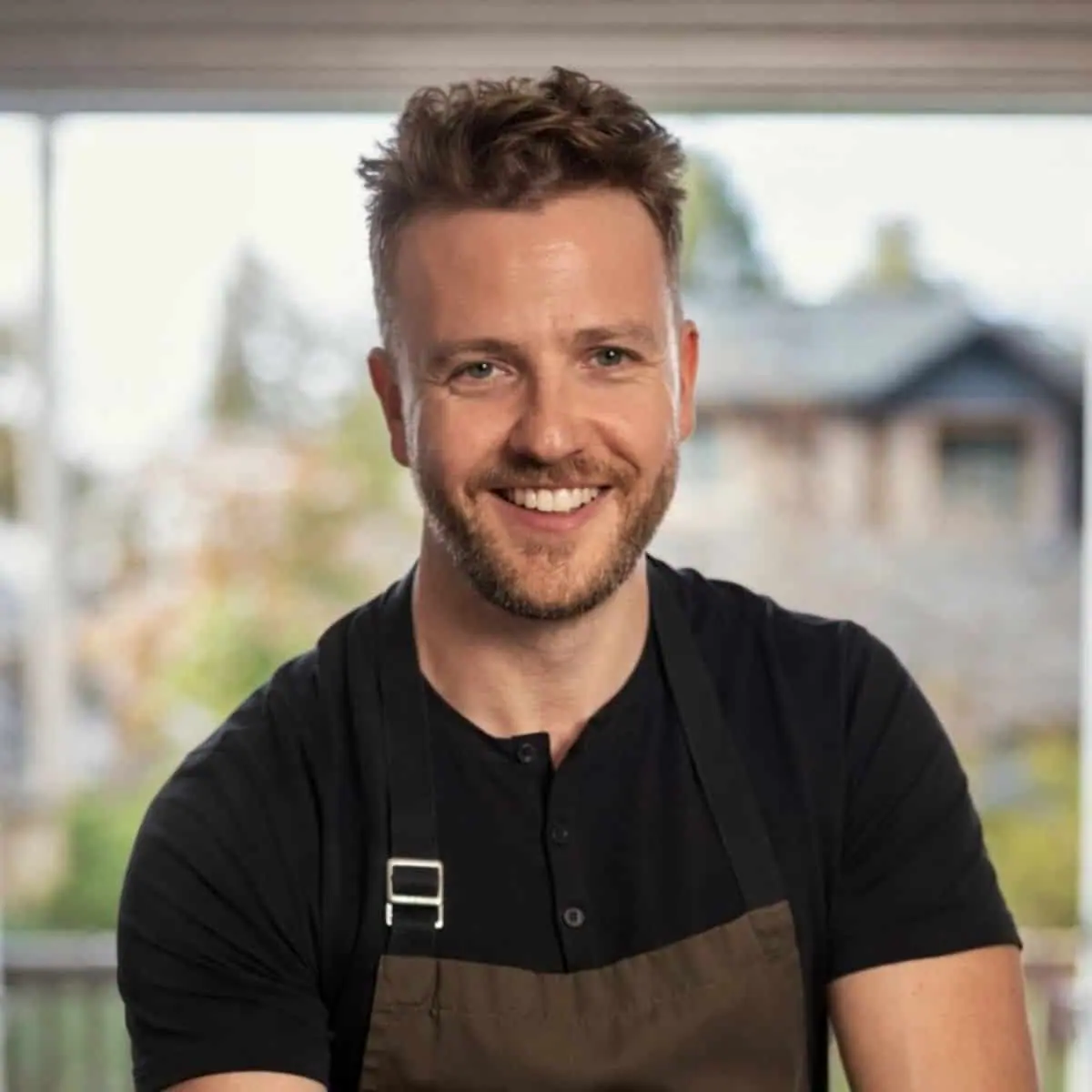 chef josh gale standing in front of a doorway wearing an apron