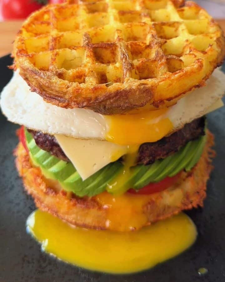Delicious breakfast burger with waffle top, egg, cheese, avocado, and beef patty.