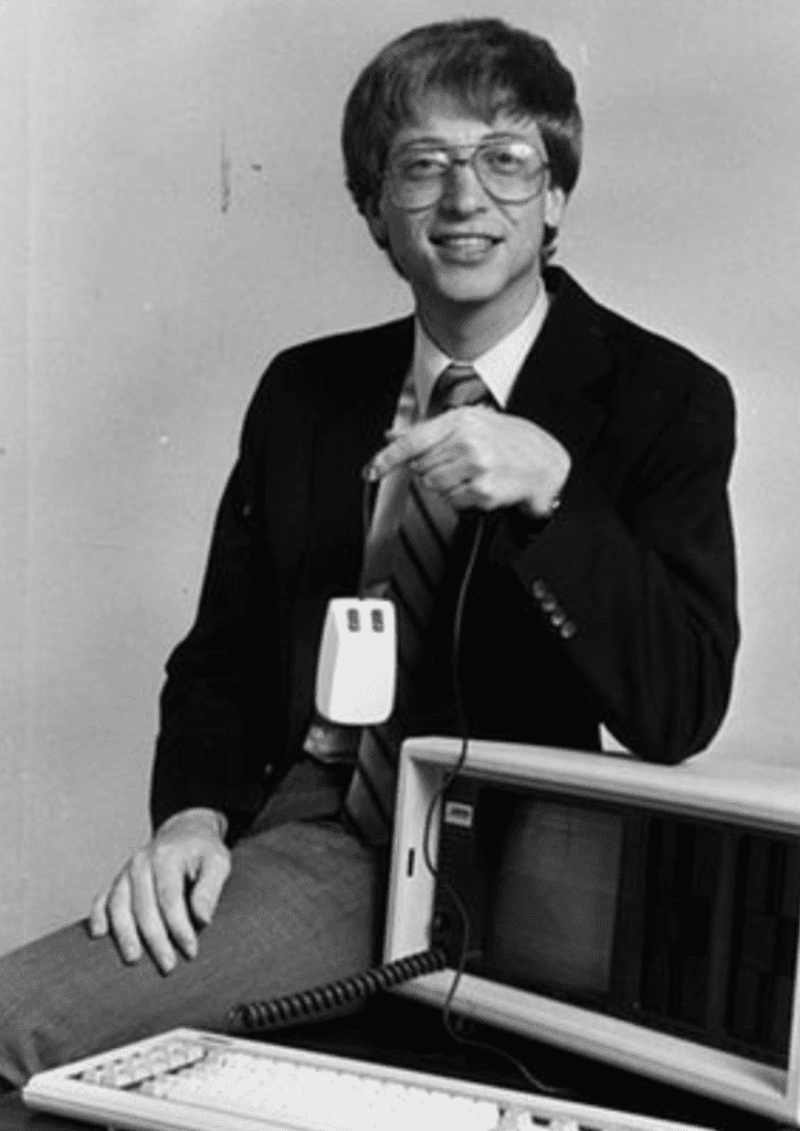 black and white photo of bill gates holding a mouse