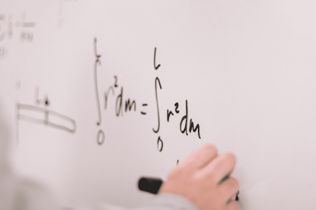 person writing math formula on whiteboard