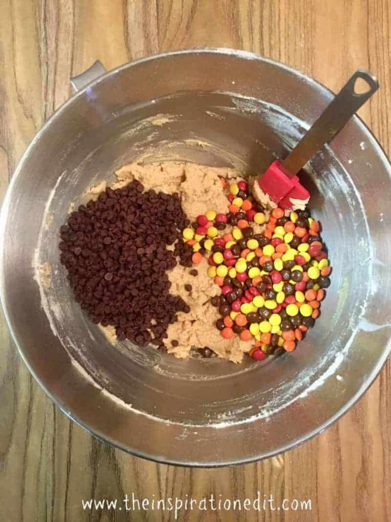 Mixing bowl with cookie dough, chocolate chips and Reese's Pieces.