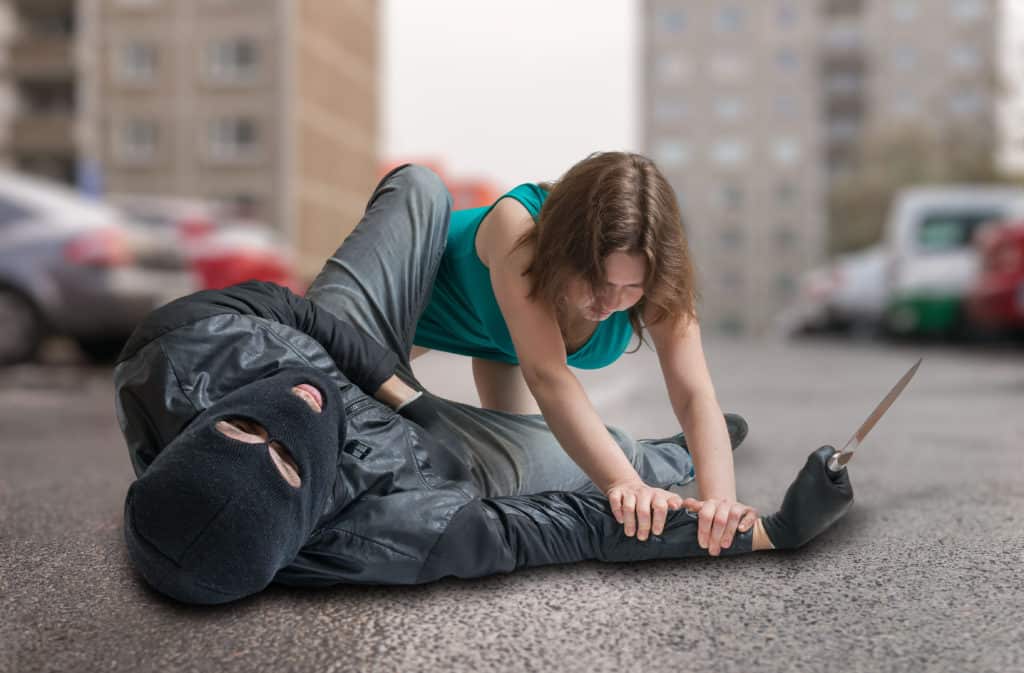 Young woman is fighting with thief on street. Self defense concept. Misconceptions about Knife Attacks
