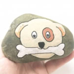 Dog face with a bone painted on a rock.