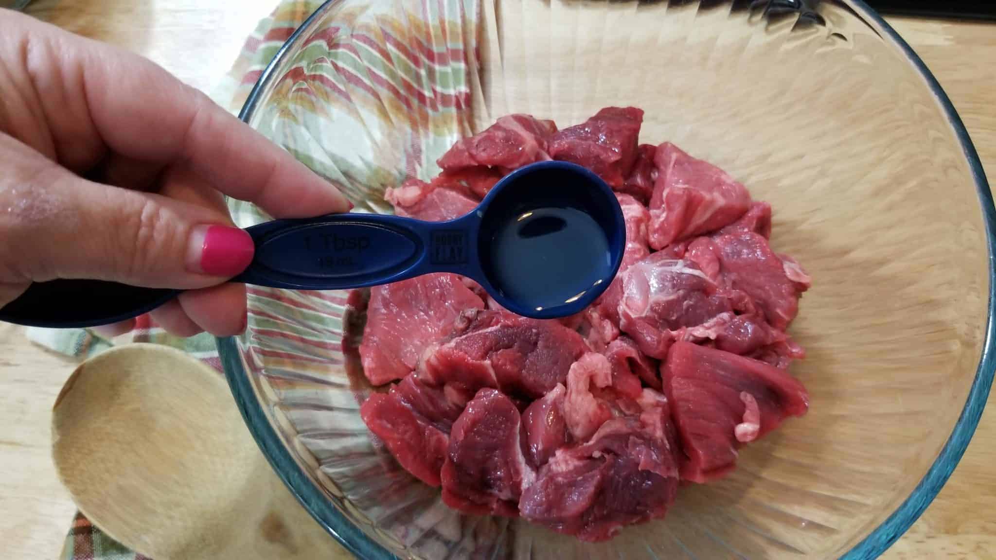 Adding oil to uncooked beef.