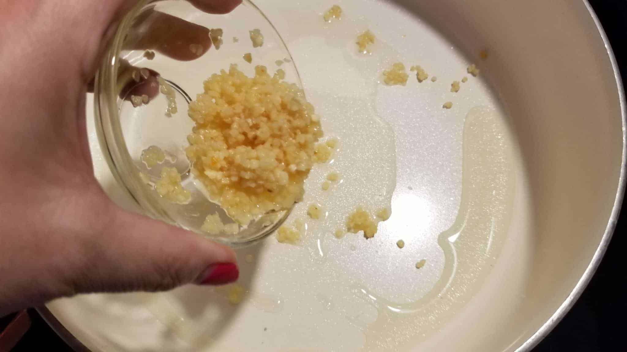 Adding minced garlic to skillet.