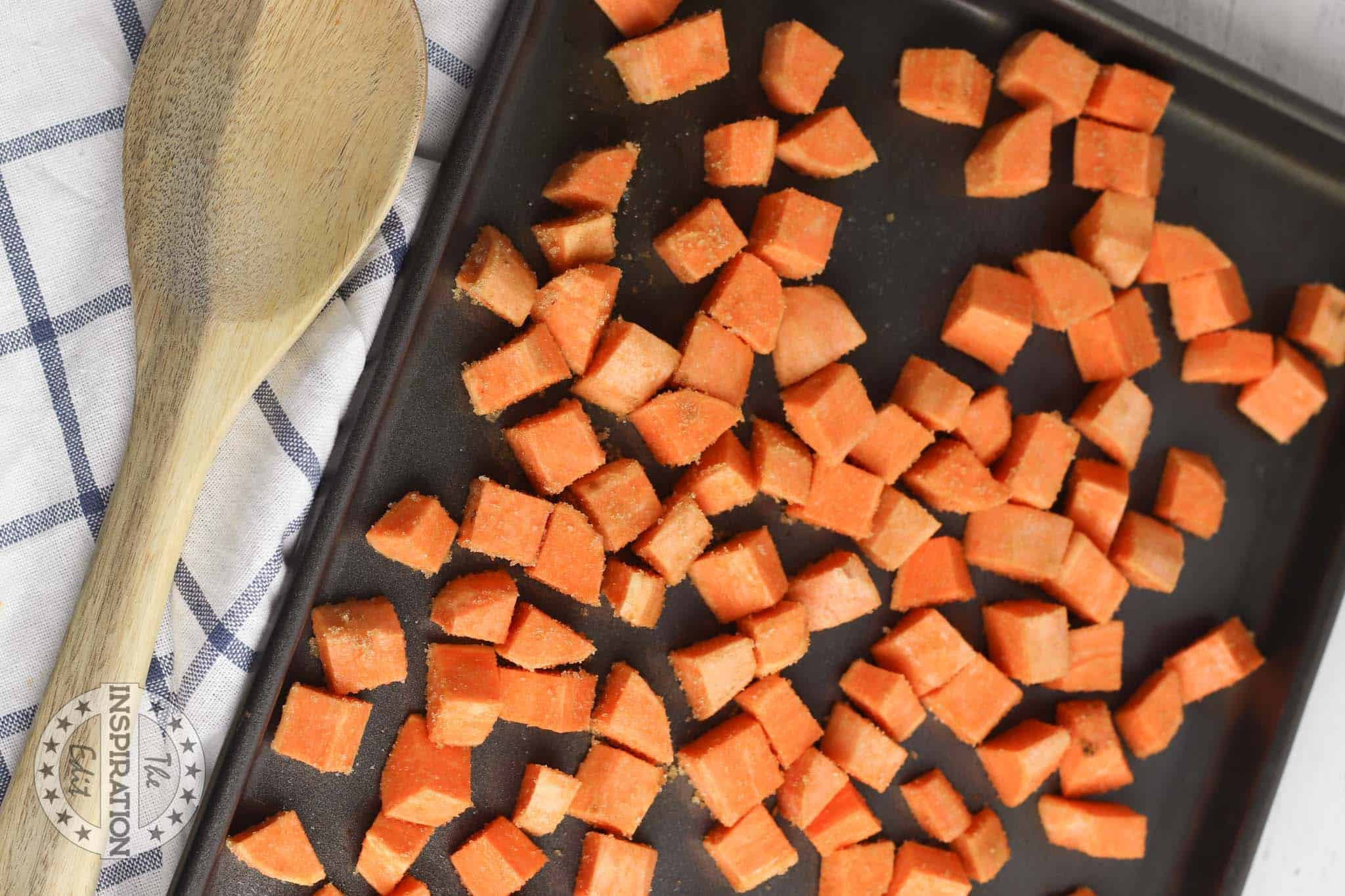 Seasoned chopped sweet potatoes on a baking tray.