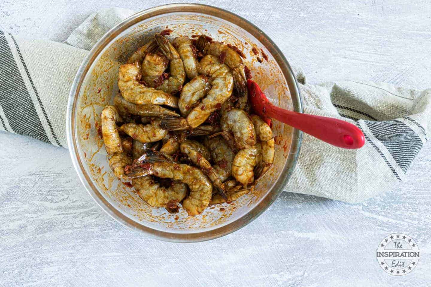 Raw shrimp covered in spices in a bowl. 