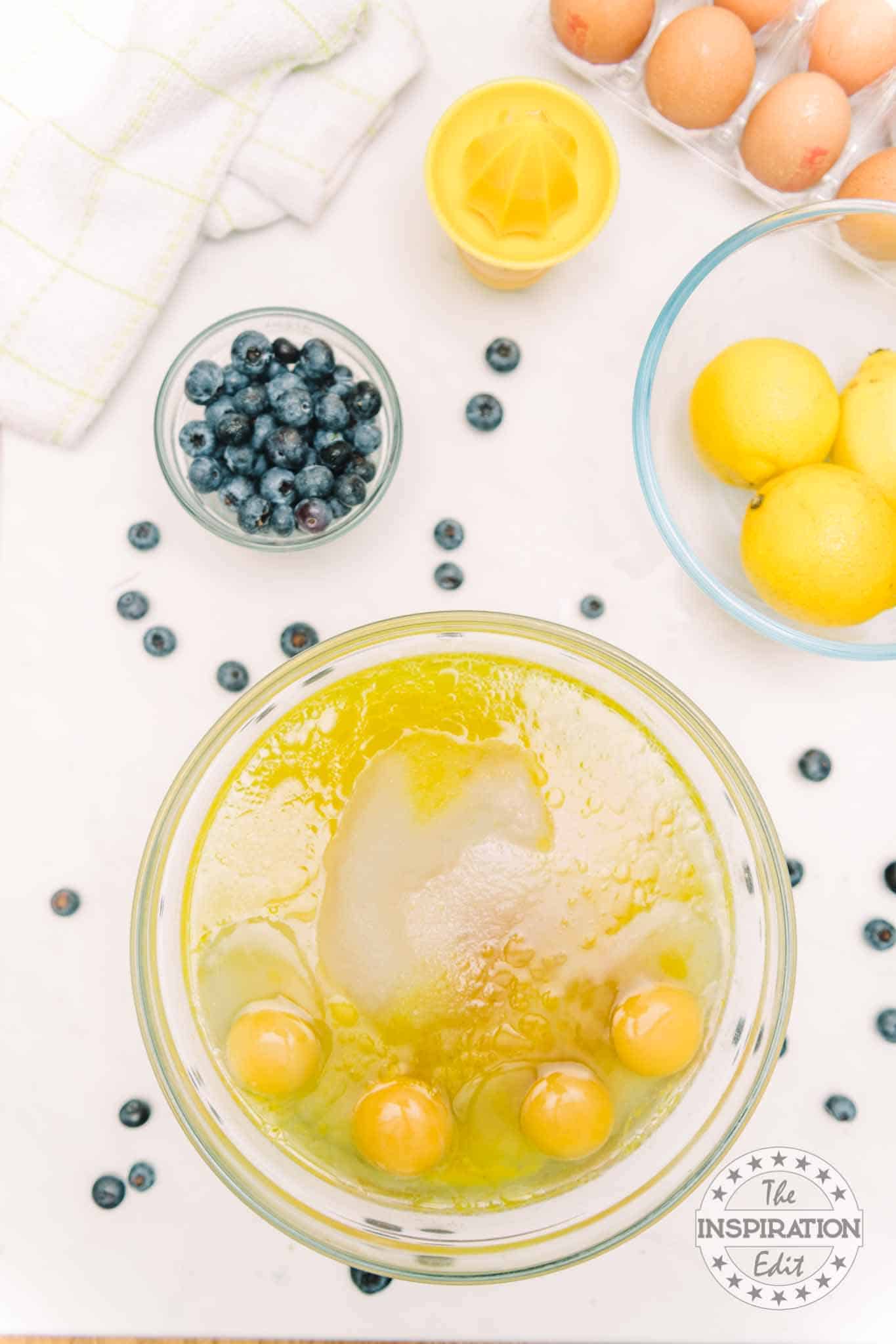 Butter, sugar, eggs, and canola oil in large bowl and one small bowl of blueberries.