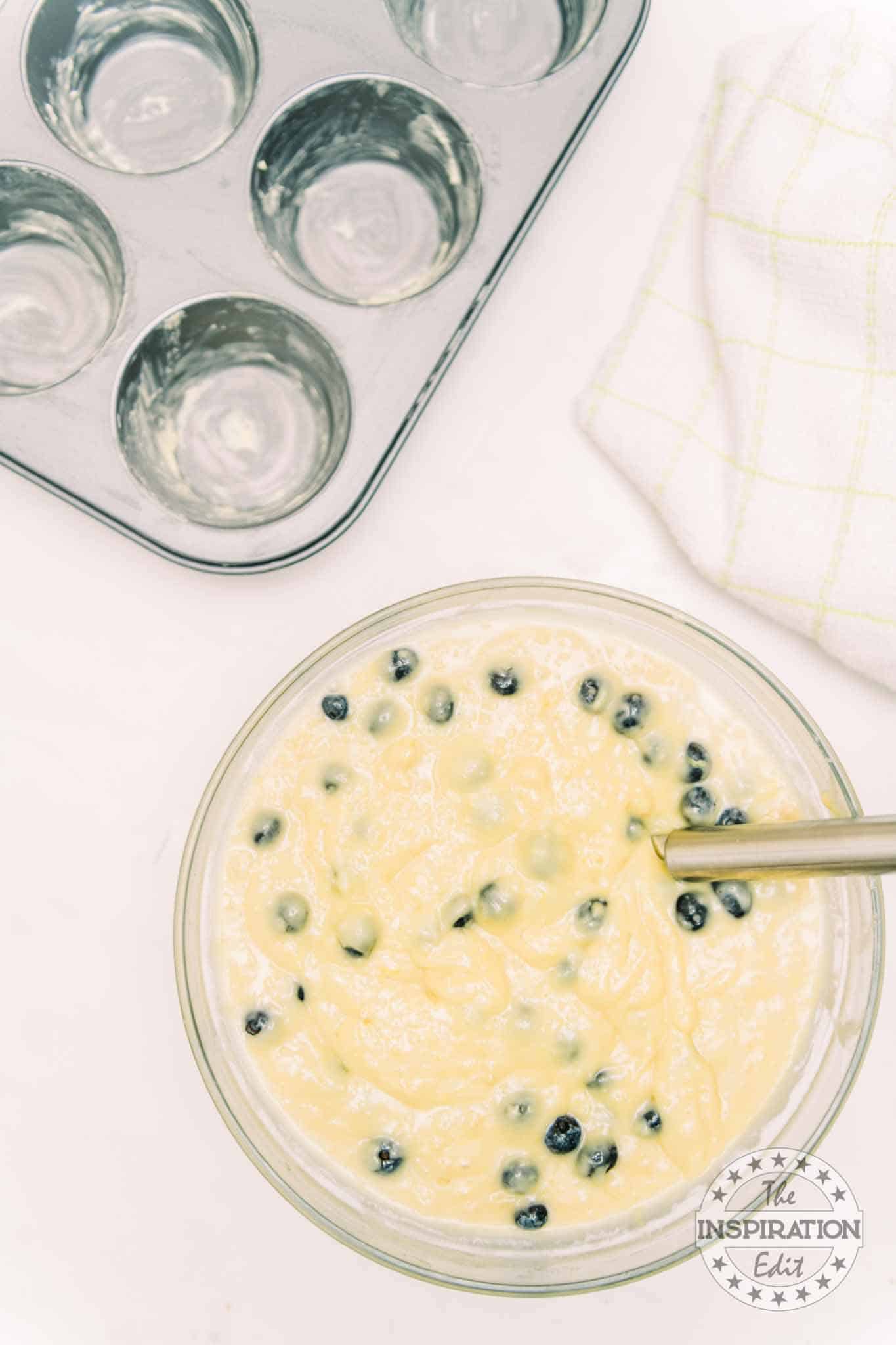 Greased muffin tray and blueberry muffins batter.