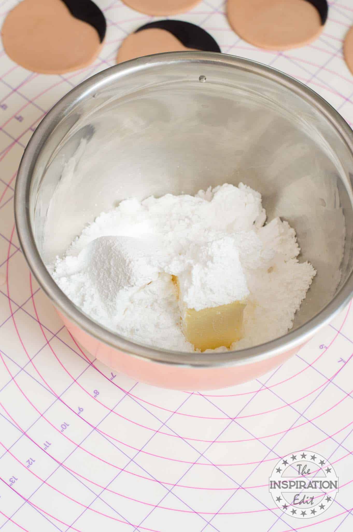 Butter, icing sugar and milk in a bowl.