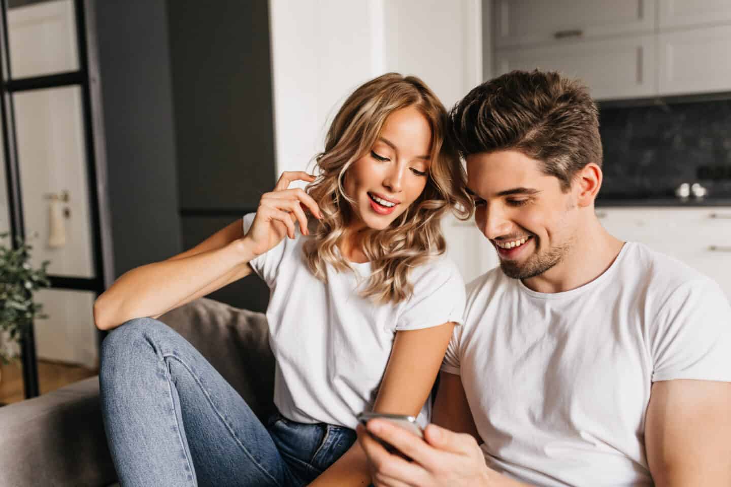 Happy Couple with Smartphone Looking on the Screen and Smiling.