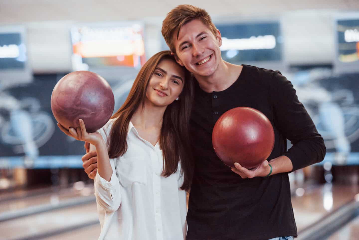 Happy Couple Holding Bowling Balls in Hands and Having a Good Time in the Club.