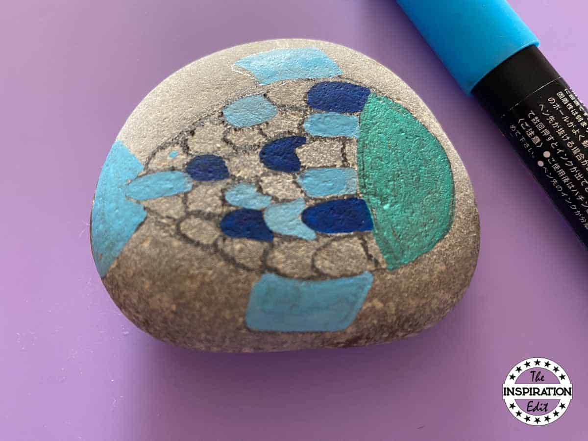 painting the fish scales on a rock.