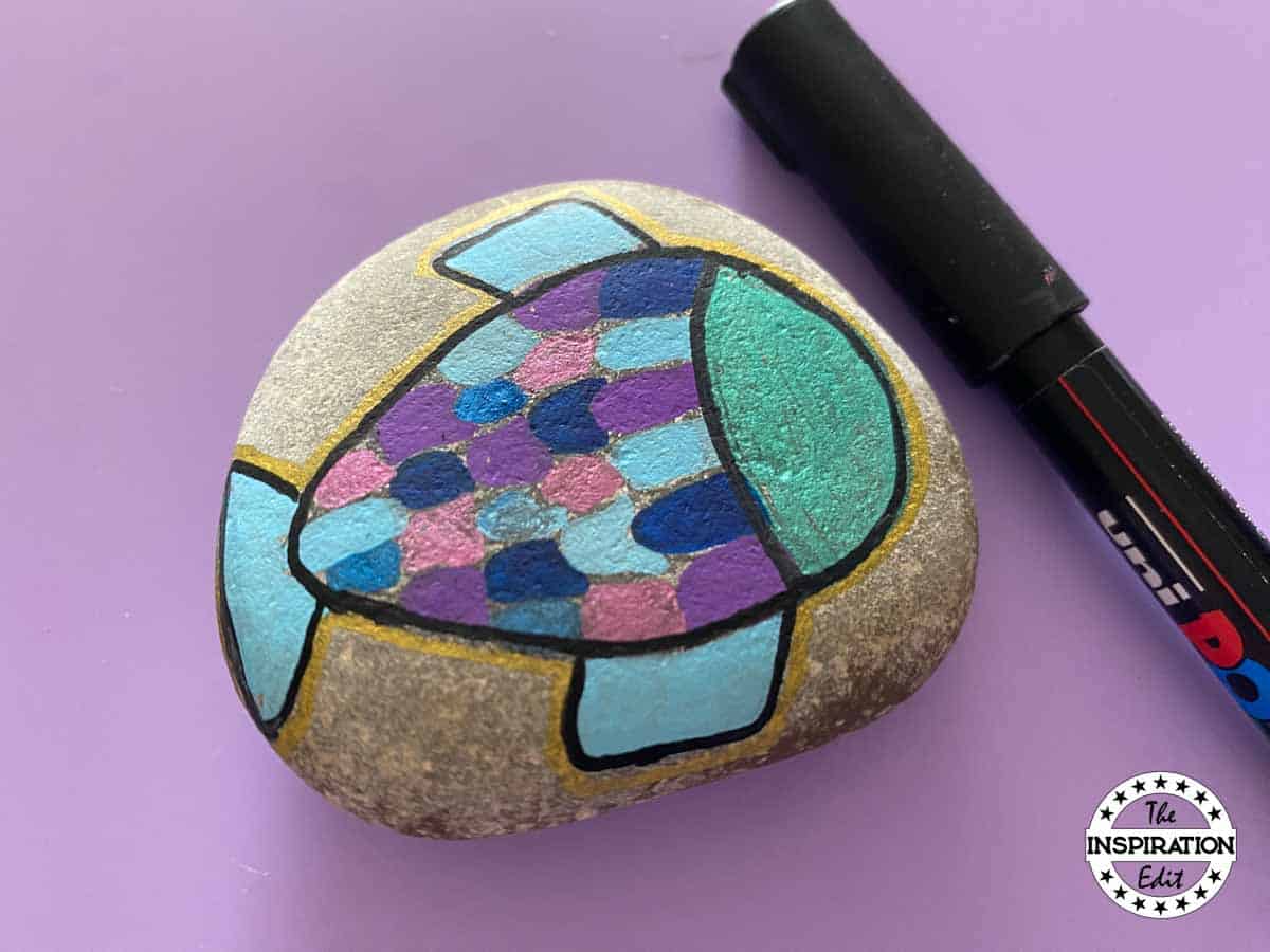adding black detail to a painted fish stone.
