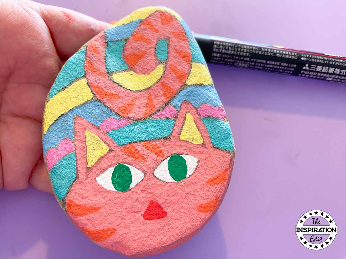 cat painted rock with green eyes. 