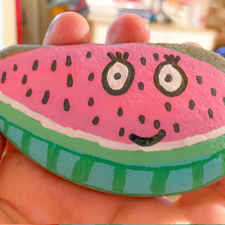 holding a watermelon painted rock stone.