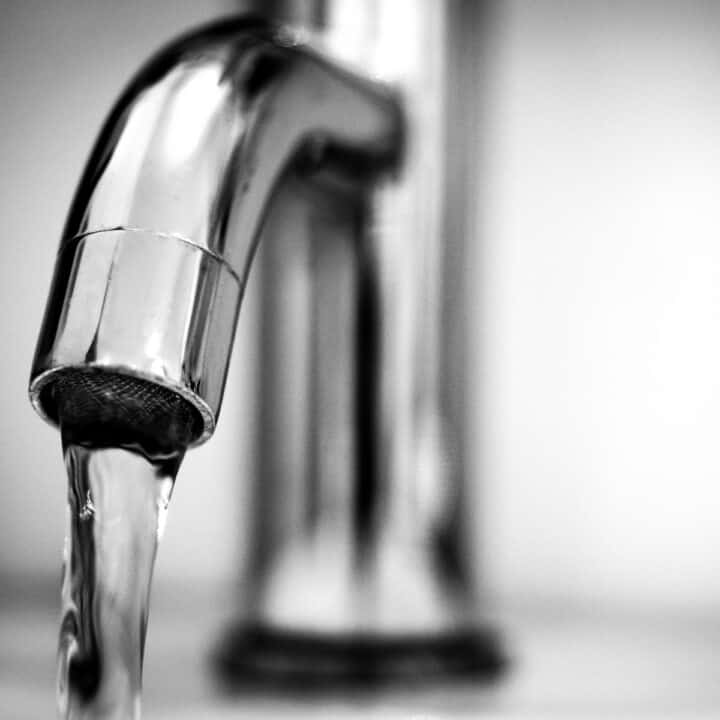 optimal health with clean water systems | Kitchen facet with the tap running.