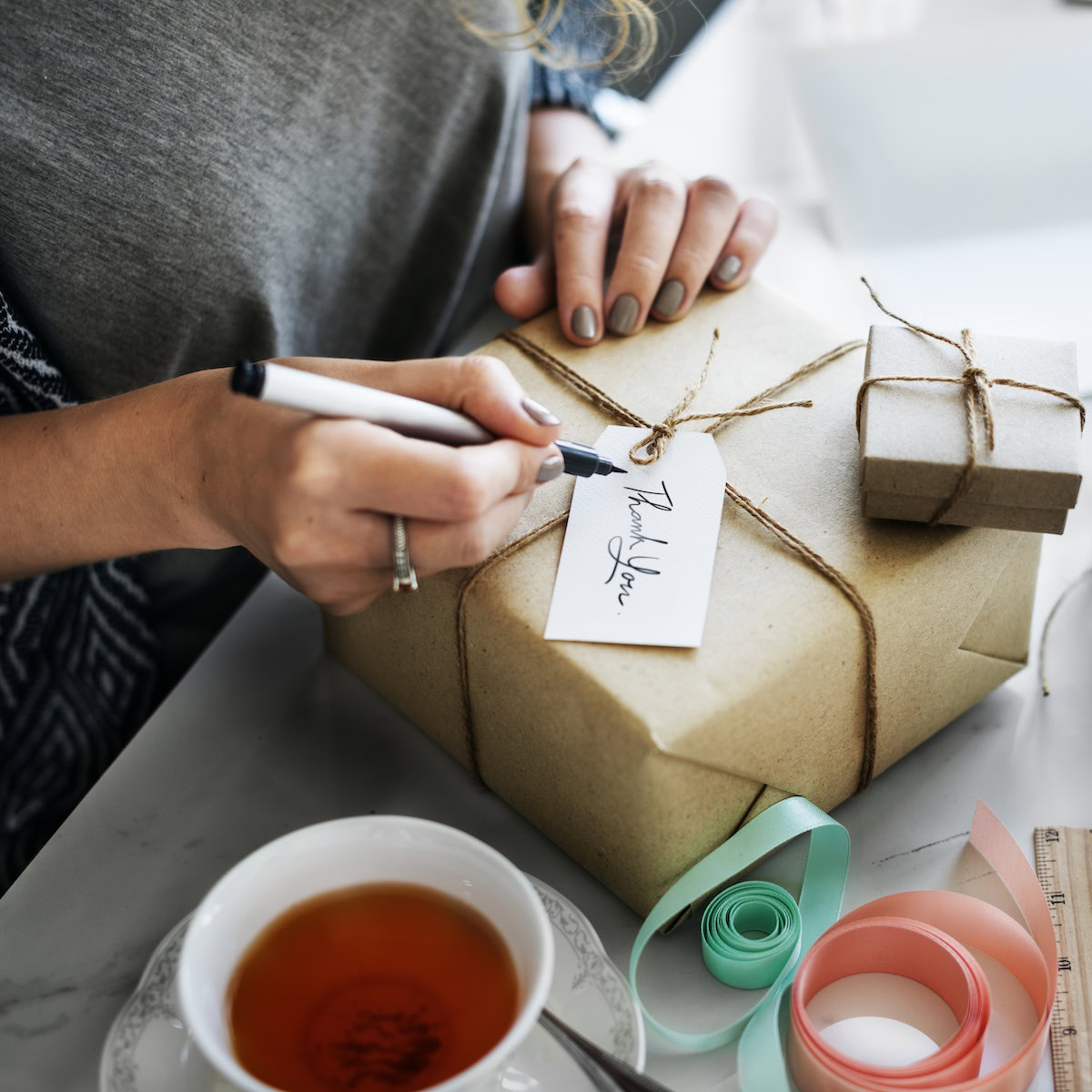 Simple gestures matter most | A woman finalising a gift with a personalised label tag.