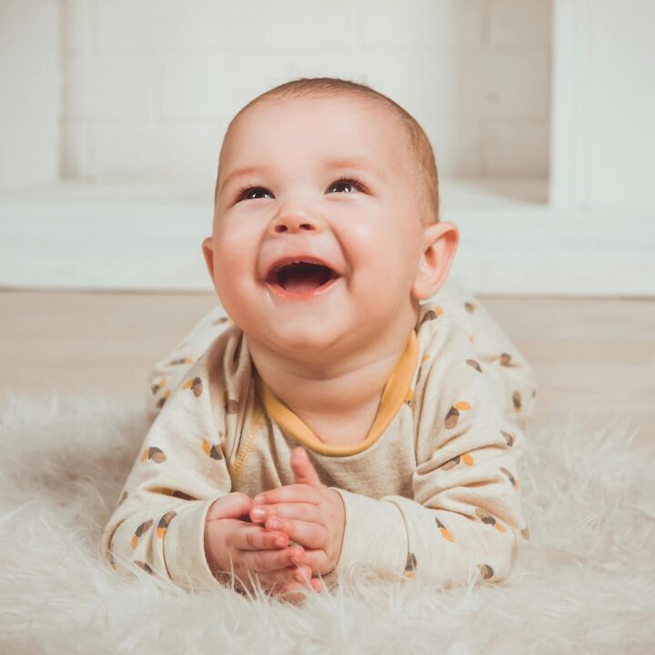 start tummy time | A baby on its tummy smiling.