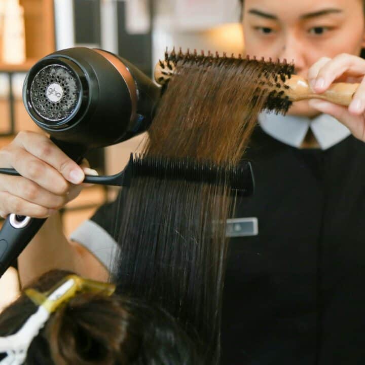 Energy-Efficient Hair Dryers | A stylist holding a hair dryer and a comb.