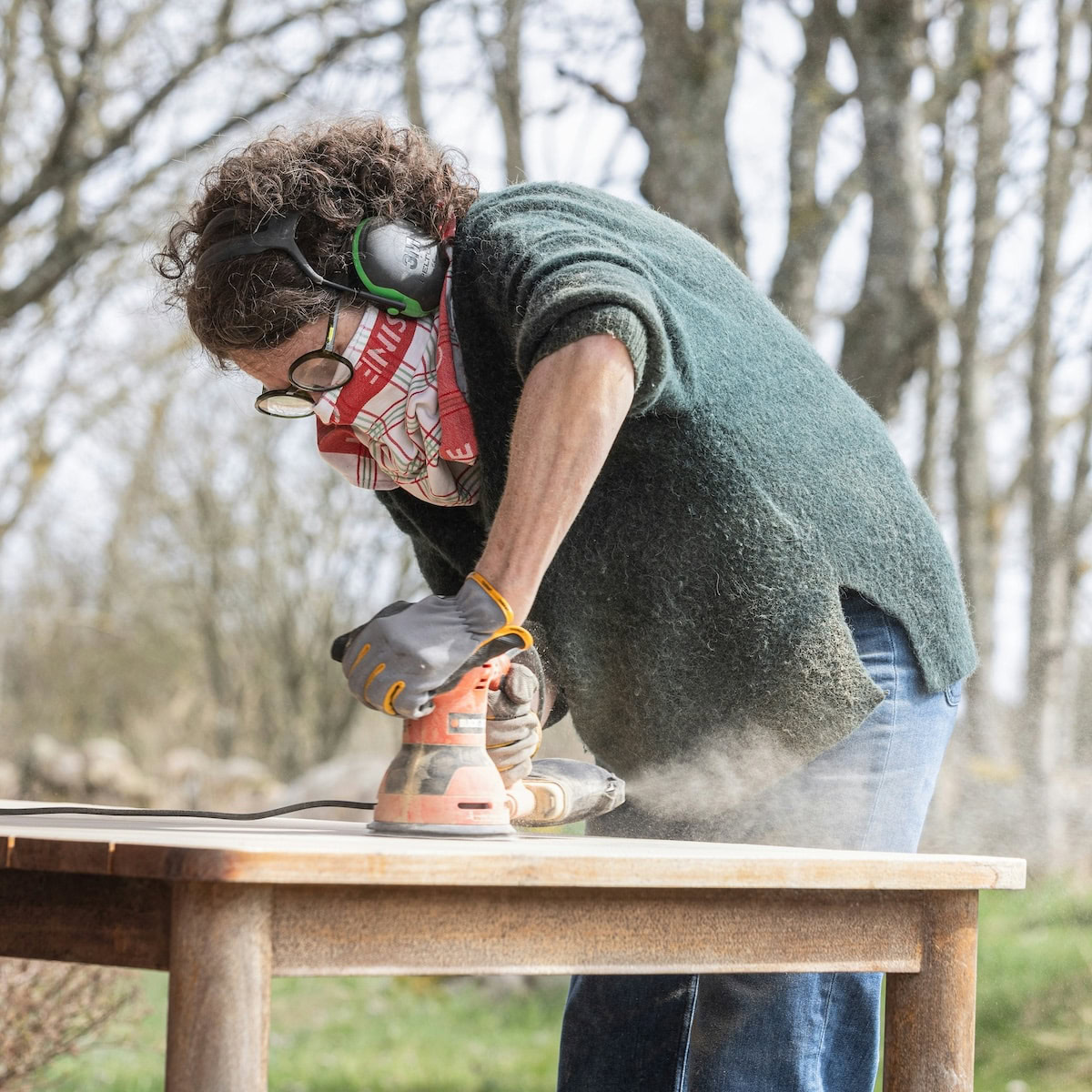 Simple DIY Renovations the Whole Family Can Do | A woman sanding a table with an orbital Sander.