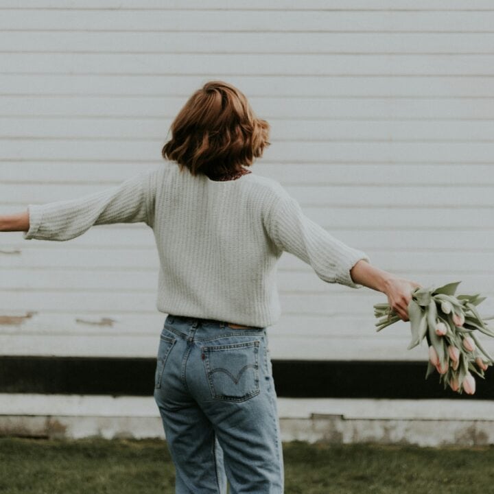 psychology behind a fresh start | A woman spinning in circles with a bunch of flowers.