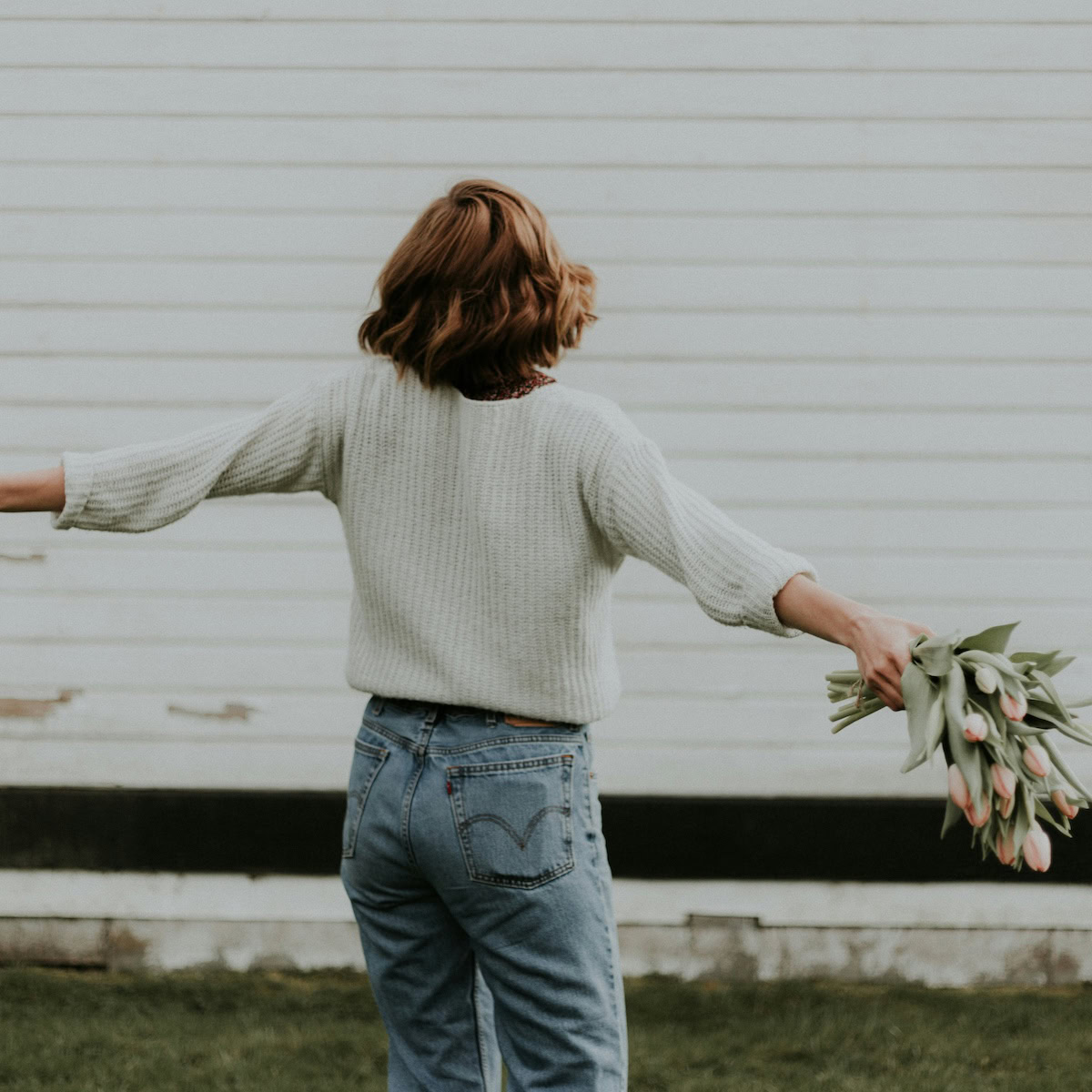 psychology behind a fresh start | A woman spinning in circles with a bunch of flowers.
