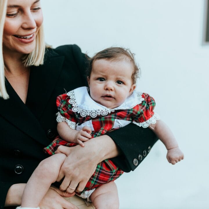 Scottish baby girl names | A mom holding a baby girl in tartan Dress.
