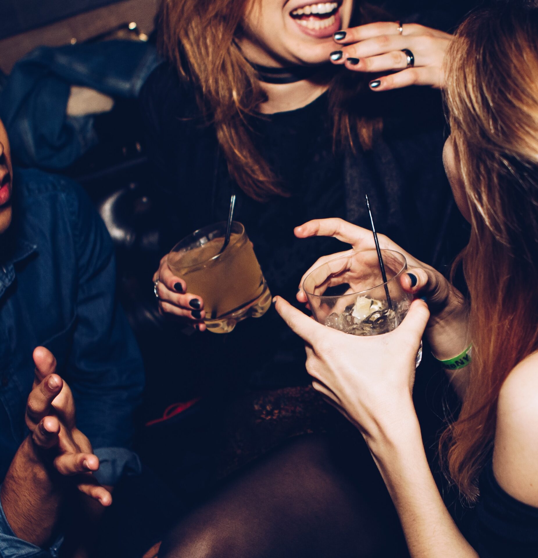 close up of two people chatting whilst drinking cocktails.