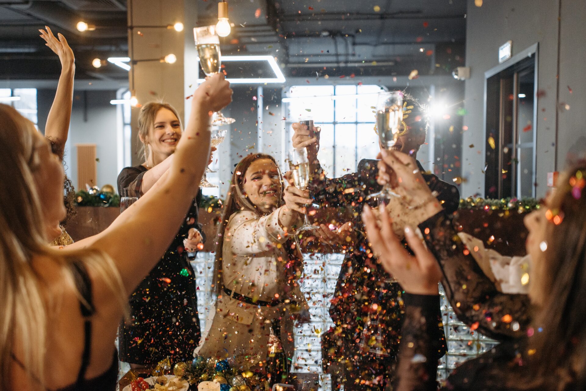 people cheers with champagne flutes with golden confetti