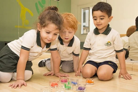 A group of children playing with colored cups in a classroom.