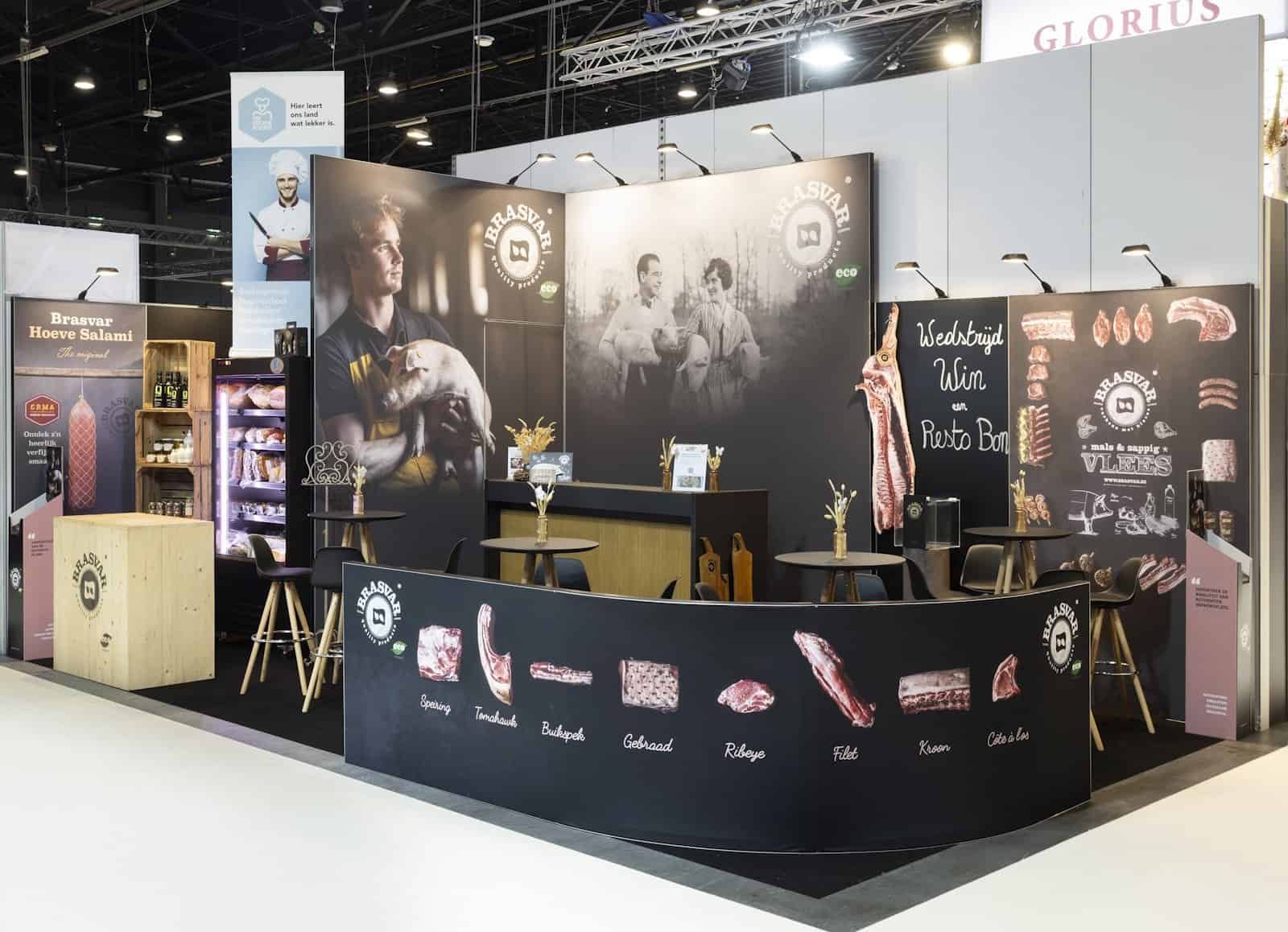 Overzicht van de Brasvar beursstand op Broodway, ingericht als een ambachtelijke slagerij met een 'chalkboard' balie en sfeervolle familiefoto's.