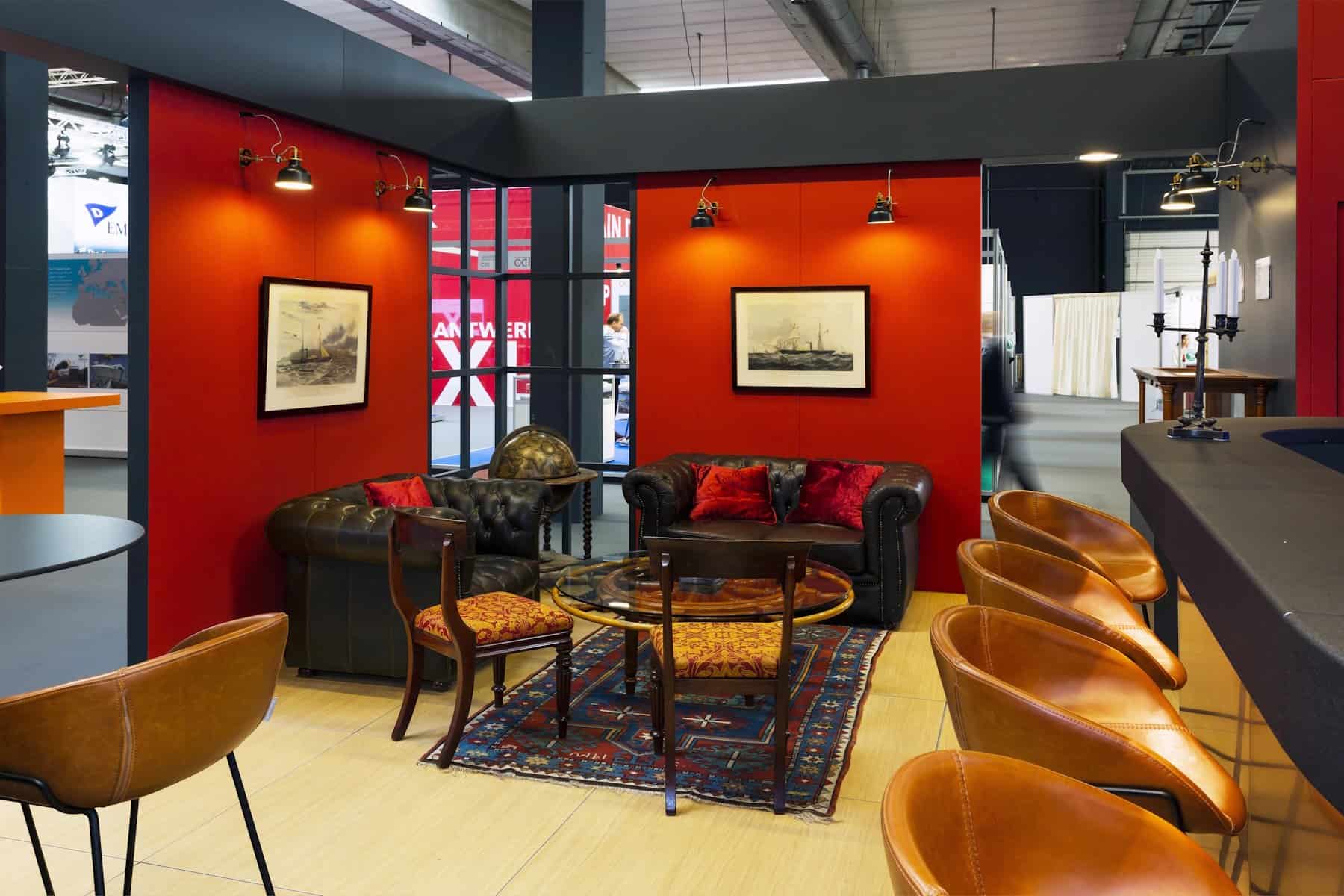 Detail van de klassieke lounge-zithoek, met een lederen Chesterfield-zetel, een warm tapijt en historische prenten aan de muur.