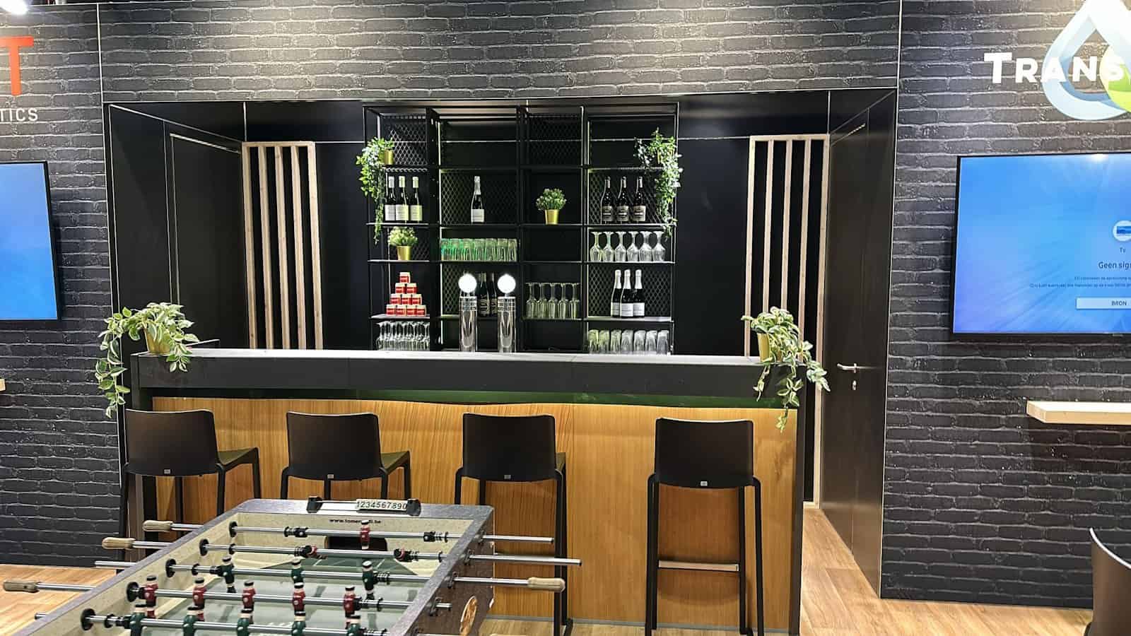 Detailopname van de professioneel uitgeruste bar en de tafelvoetbaltafel, elementen die een informele sfeer creëren.