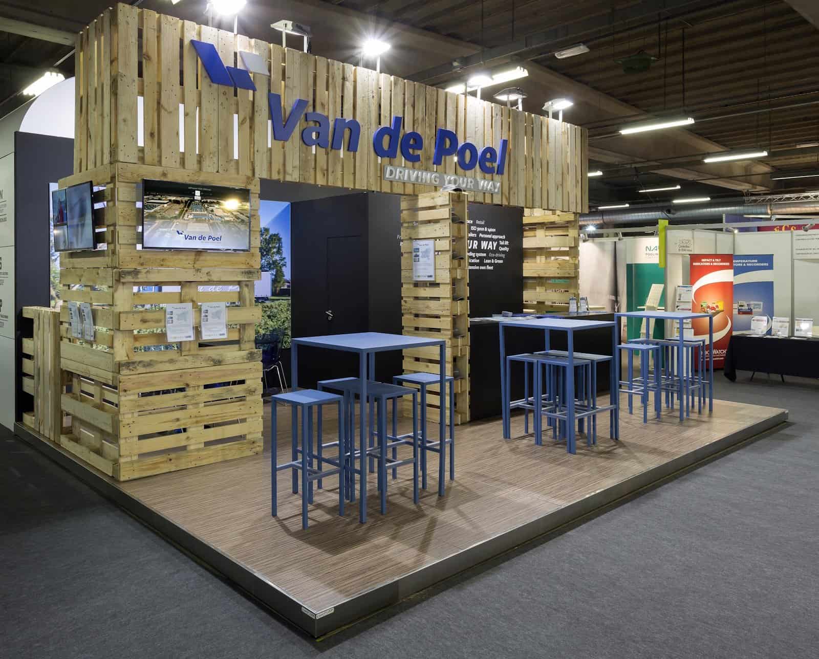 Beursstand voor transportbedrijf Van de Poel, met een afgesloten ruimte en tafeltjes in de huisstijlkleuren van het bedrijf.