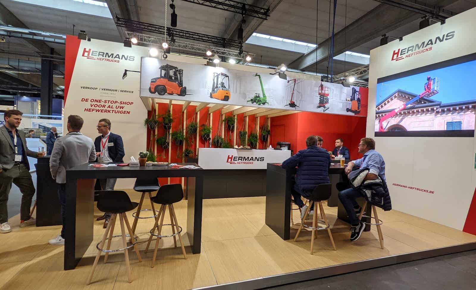 Overzicht van de Hermans Heftrucks beursstand die met een grote productbanner en een ruime netwerkzone een maximale impact creëert zonder fysieke machines.