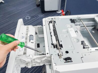 Un técnico usa un destornillador para reparar el mecanismo interno de una impresora que no imprime y necesita solución.