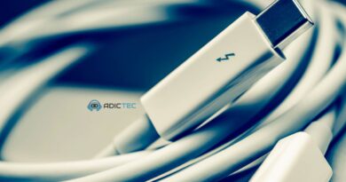 Un cable Thunderbolt 5 enrollado, enfocado en el conector, sobre un fondo azul oscuro.