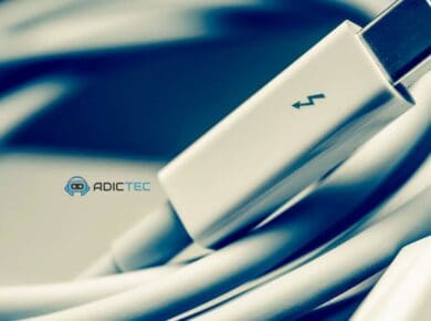 Un cable Thunderbolt 5 enrollado, enfocado en el conector, sobre un fondo azul oscuro.