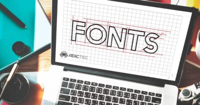 Imagen de un portátil mostrando un diseño de tipografía "FONTS" sobre una cuadrícula, ilustrando el proceso de creación de fuentes. Se observan también útiles de escritura y diseño gráfico a su alrededor.