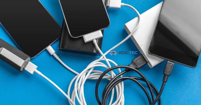 Imagen de varios smartphones y tablets conectados a cargadores y baterías portátiles, sobre un fondo azul. La imagen ilustra el tema de la carga de dispositivos móviles.