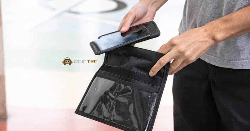 Mano introduciendo un teléfono móvil en una funda negra antirrobo Faraday. La funda tiene un diseño discreto y profesional, ideal para proteger la privacidad digital.