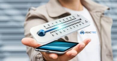 Mano sosteniendo un teléfono móvil con un termómetro digital flotando encima. Consejos para enfriar un teléfono sobrecalentado.