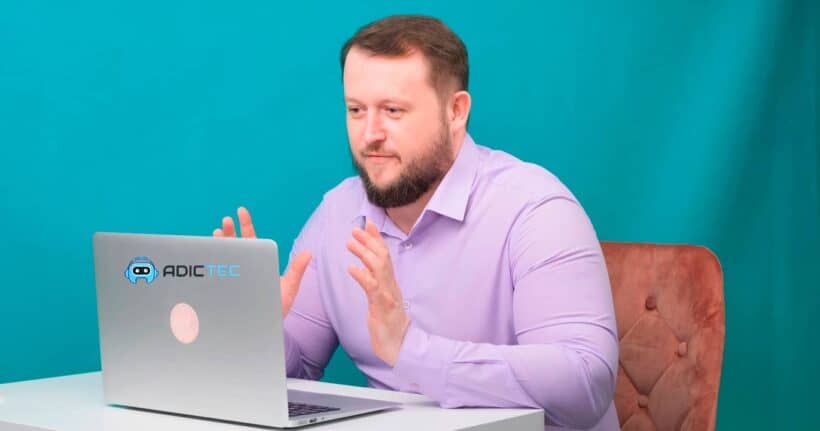 Hombre sentado frente a un portátil, explicando cómo solucionar un zumbido en un PC. Solución de problemas.